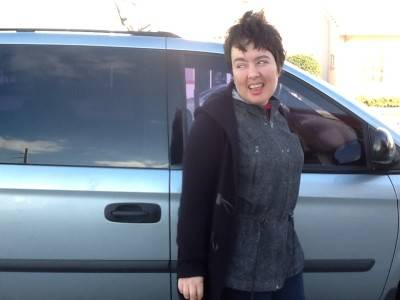 Photograph of Amy Sequenzia, woman with white skin and dark brown hair smiling in front of a blue van.