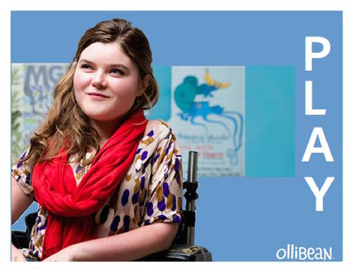 Photograph of smiling teenage girl with long brown hair and white skin. She is wearing a multicolored shirt and red scarf and sitting in a wheelchair. MGMT poster is in the background and PLAY and Ollibean logo in white.