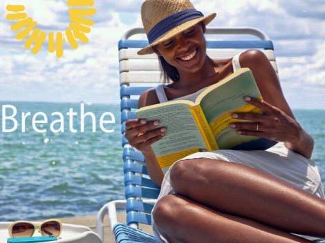 woman reading a book in lounge chair with ocean in background