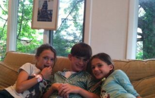 picture of girl, boy and girl sitting on couch smiling