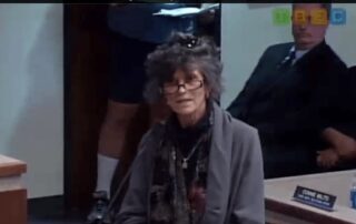 woman with black and gray hair speaking at podium