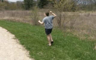 Boy with gray shirt running in grass