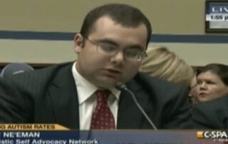 Image description: Photograph of screenshot of C-SPAN a light skinned man with black hair. He is wearing glasses and a dark grey suit, light shirt and maroon tie. Ari Ne'eman Autistic Self Advocacy Network