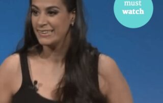 image description . Photograph of Maysoon Zayid, woman with long brown hair . She is smiling and wearing a black tank top. White text reads "MAYSOON ZAYID" . In upper right hand corner of image there is a turquoise circle with white text that reads "Must Watch"